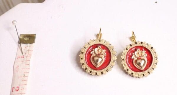 A pair of earrings with red and gold designs.