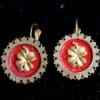 A pair of earrings with red and gold flowers.