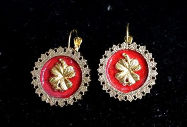 A pair of earrings with red and gold flowers.