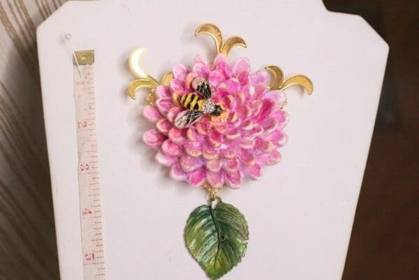 A pink flower with leaves and a bee on it.
