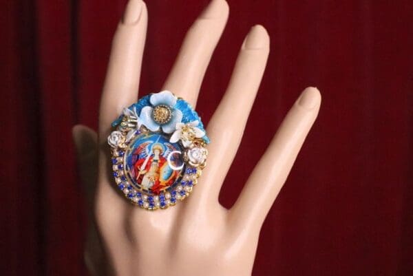 A hand wearing a ring with a picture of jesus.