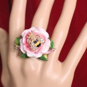 A hand wearing a ring with a flower on it