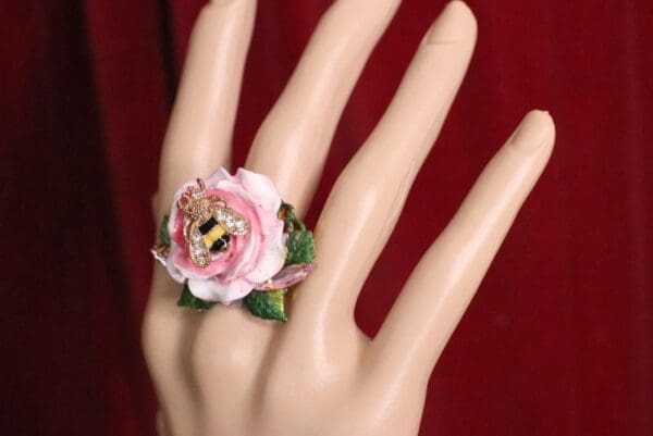 A hand with a ring on it's finger and the fingers are decorated with flowers.