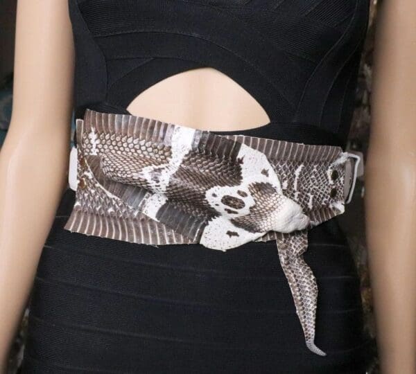 A woman wearing a black dress with a belt around her waist.
