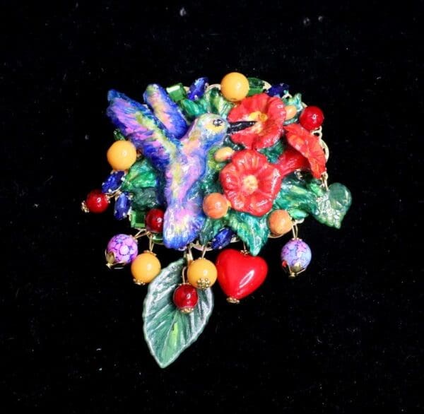 A colorful brooch with flowers and leaves on it.