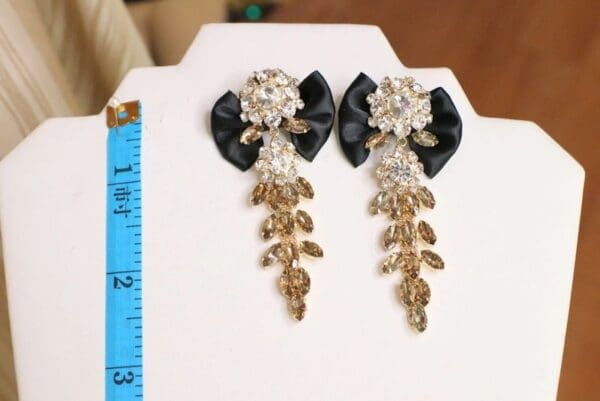 A pair of earrings with black bows and gold leaves.