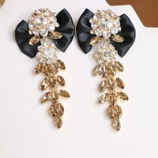 A pair of black and gold earrings with rhinestones.