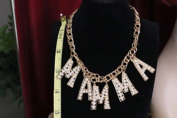 A necklace that says mama and is being measured.