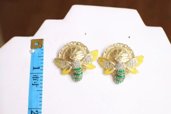 A pair of earrings with a bee on them.