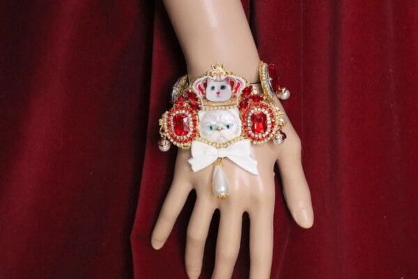 A hand wearing a red and white bracelet with a bow.