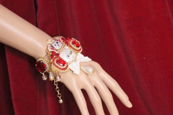 A hand wearing a bracelet with red flowers on it.
