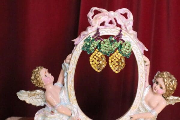 A picture frame with two pineapples hanging from it.