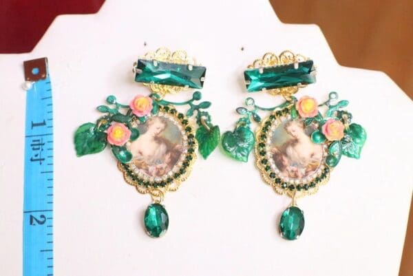 A pair of green earrings with a picture on them.