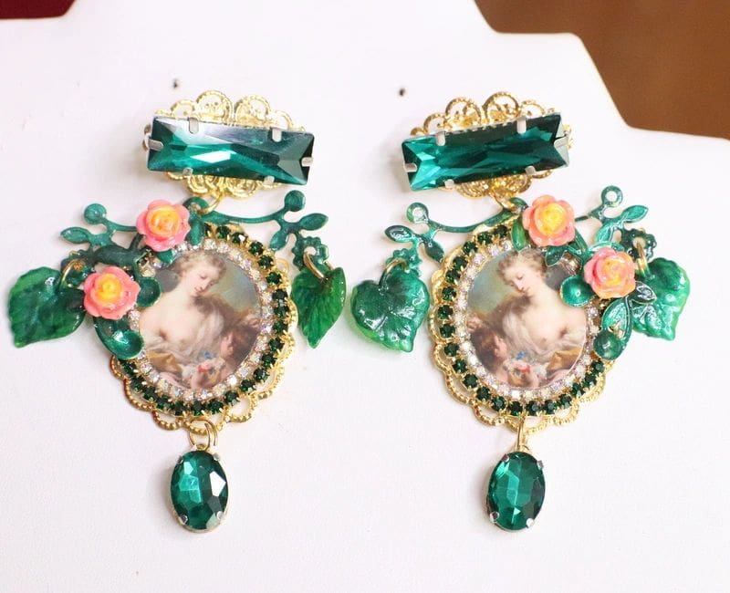 A pair of earrings with green stones and flowers.