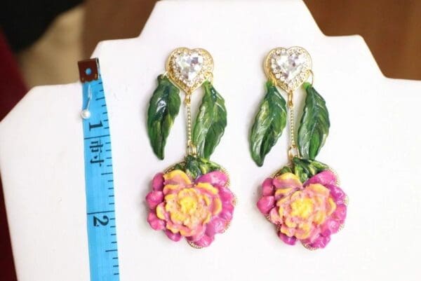 A pair of earrings with leaves and flowers.