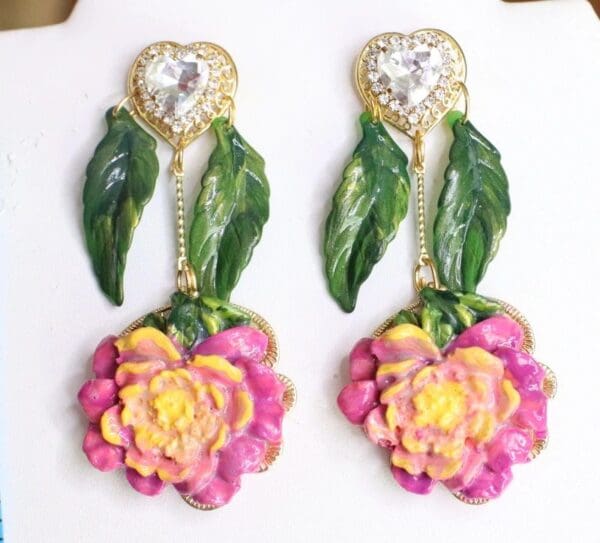 A pair of earrings with flowers and leaves.
