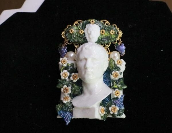 A white bust with flowers and grapes on it.