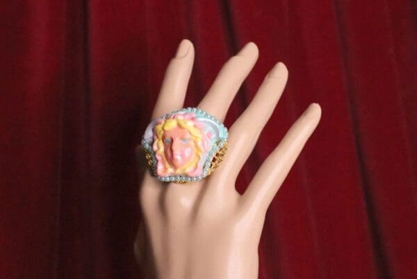 A hand wearing a ring with a face on it