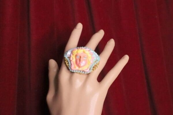 A hand wearing a ring with a picture of a person on it.