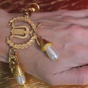A hand with a gold bracelet and pearls on it