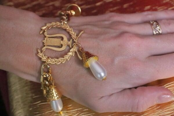 A hand with a gold bracelet and pearls on it