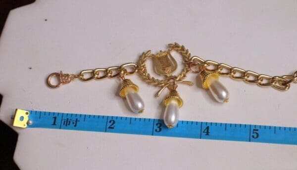 A gold chain with three pearls on it.