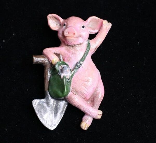 A pink pig with a green bag and a shovel.