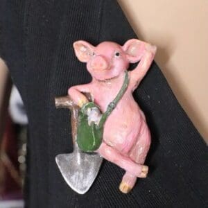 A pink pig hanging on the wall with a shovel.