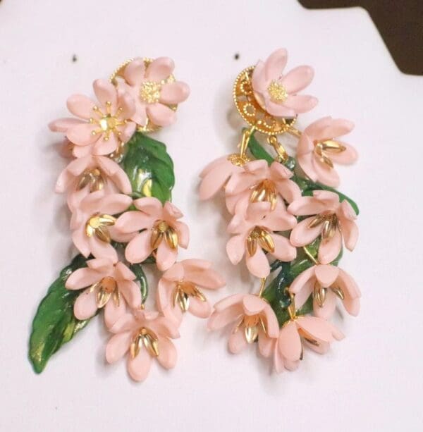 A pair of pink flower earrings on top of a white table.