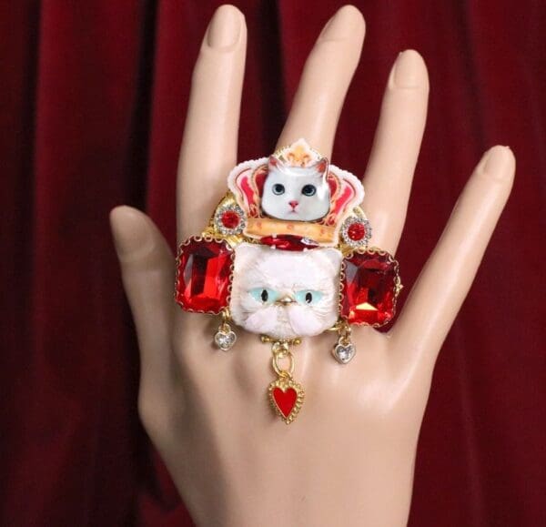 A hand with a ring on it and a cat in the middle of it