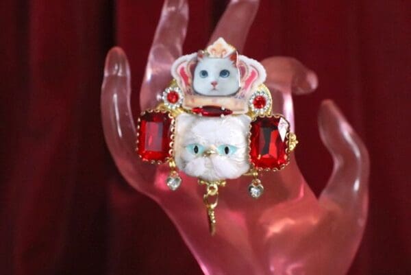 A hand holding a cat with jewels on it