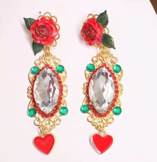 A pair of earrings with red hearts and green beads.