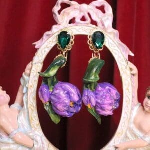 A pair of earrings with purple flowers and green leaves.
