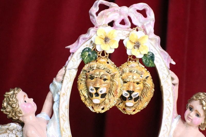 A pair of earrings with flowers and a lion head.