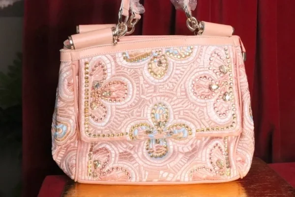 A pink purse with some gold and white designs