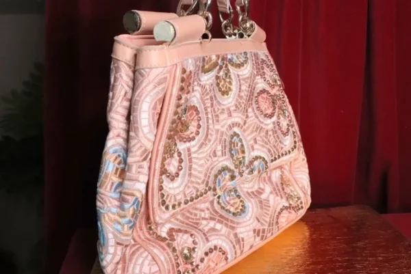 A pink purse sitting on top of a wooden table.