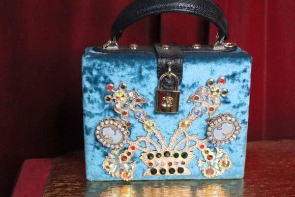 A blue purse with jewels on it sitting on top of a table.