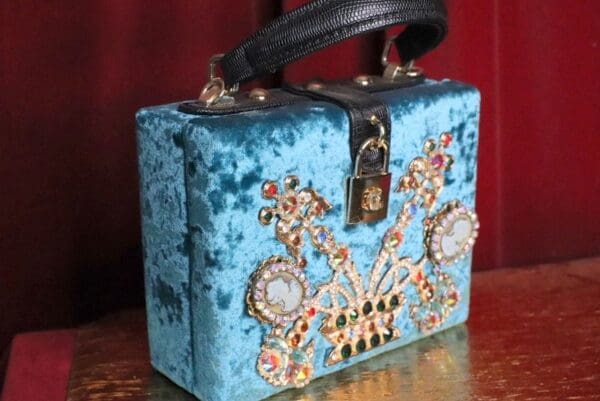 A blue purse with jewels on it sitting on top of a table.