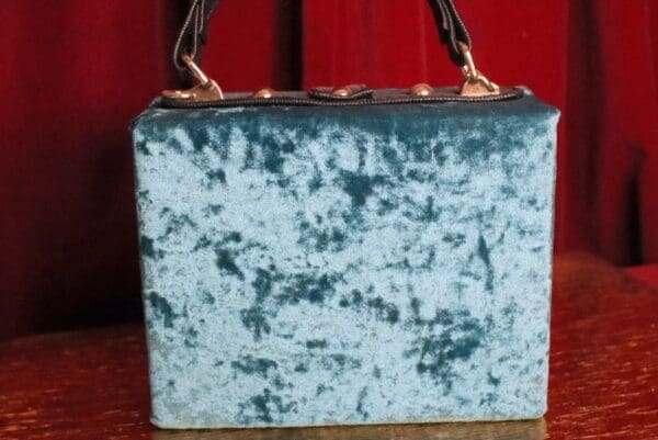 A blue purse sitting on top of a wooden table.