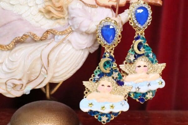 A pair of earrings with angels and stars on them.