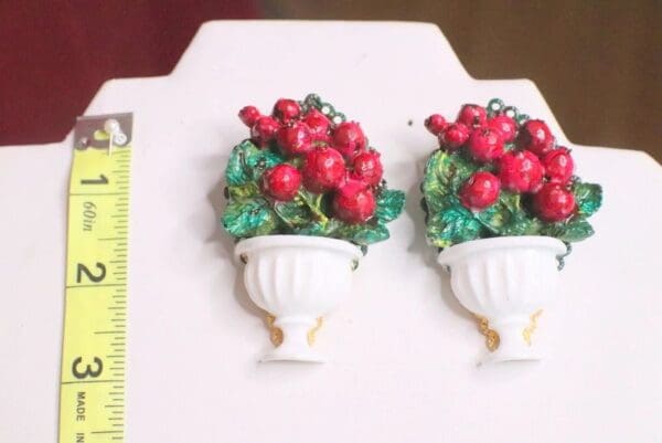Two white vases with red flowers in them.
