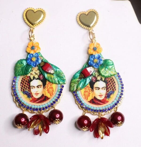 A pair of earrings with frida kahlo and flowers.