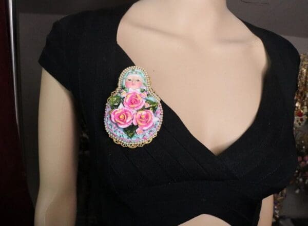A woman wearing black shirt and pink flower brooch.