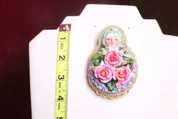 A picture of a matryoshka doll with pink roses on it.