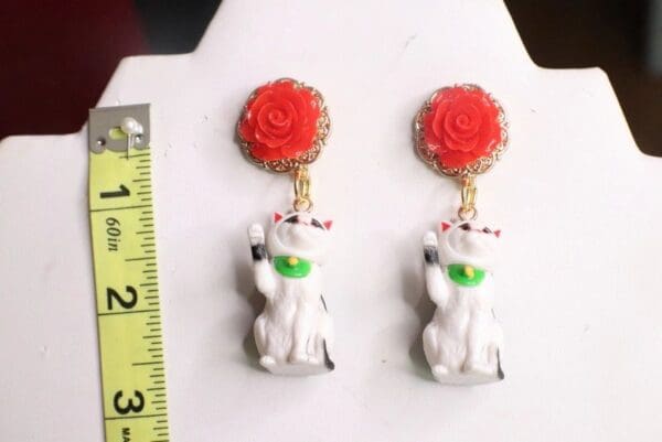 A pair of earrings with a cat and flower on them.