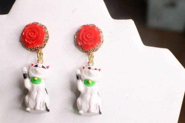 A pair of earrings with cats and flowers on them.