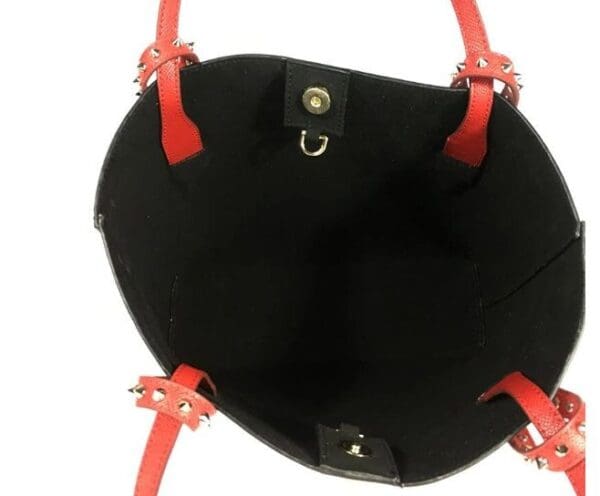 A black purse with red handles and a small hole in the middle.
