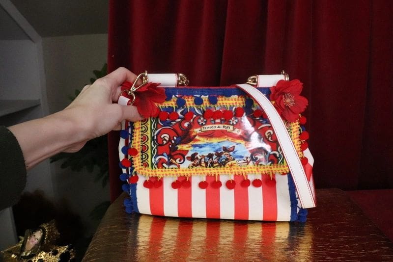 A hand is holding onto a circus themed purse.