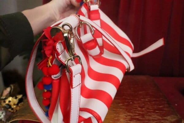 A woman holding onto some red and white striped purse