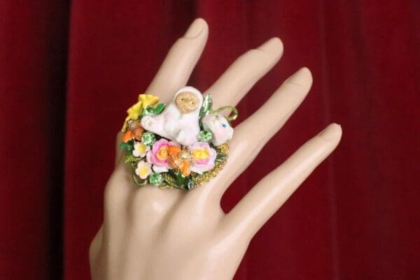 A hand wearing a ring with flowers on it